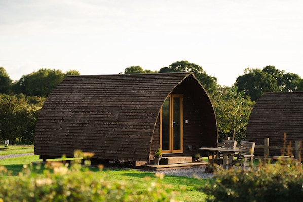 Une cabane en bois avec un toit incurvé, une porte et une petite véranda avec une table et des chaises.