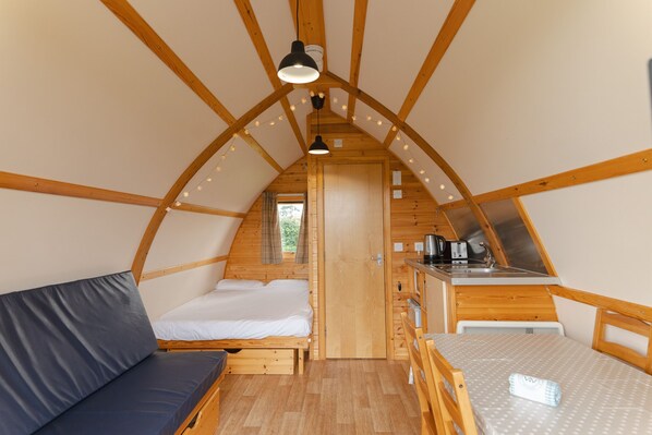 Un intérieur chaleureux, avec des éléments en bois, comprenant un lit en mezzanine, une petite cuisine et un coin repas.
