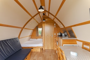 Un intérieur chaleureux, avec des éléments en bois, comprenant un lit en mezzanine, une petite cuisine et un coin repas.