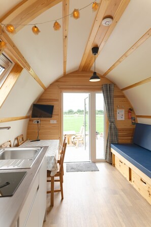 A cozy, wooden interior with a kitchen, dining area, and a large window overlooking a green landscape. - En-suite Wooden Cabin With Hot Tub (Langho)