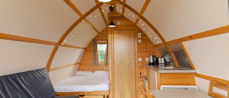 A cozy, wooden interior with a loft bed, a small kitchenette, and a dining area.