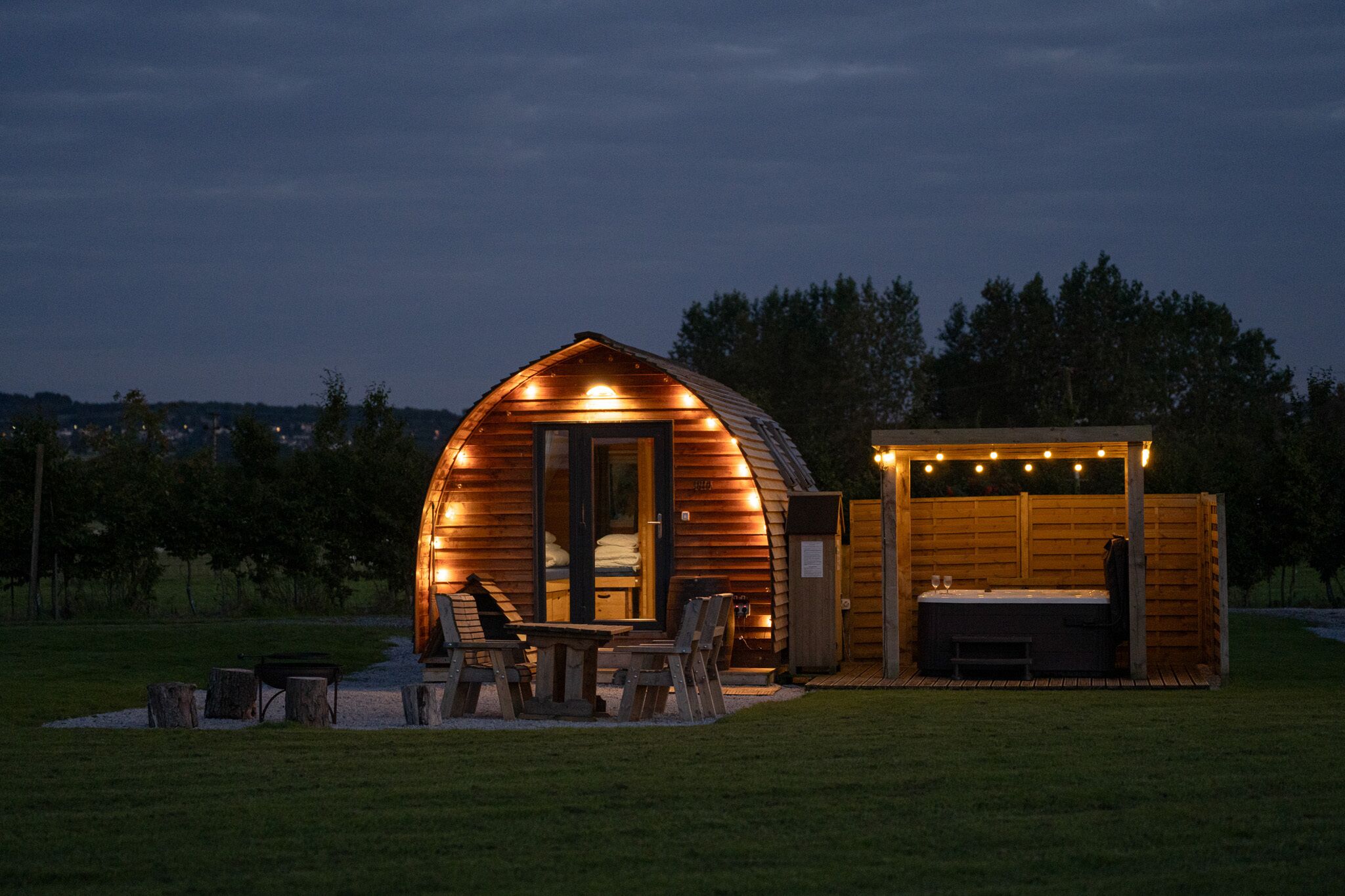 A wooden cabin with a covered patio, a hot tub, and a small deck area.