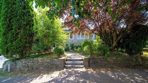 A stone staircase leading to a house surrounded by lush greenery and trees.