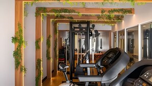 Une salle de sport équipée de matériel d’exercice, avec des poutres en bois et des plantes vertes.