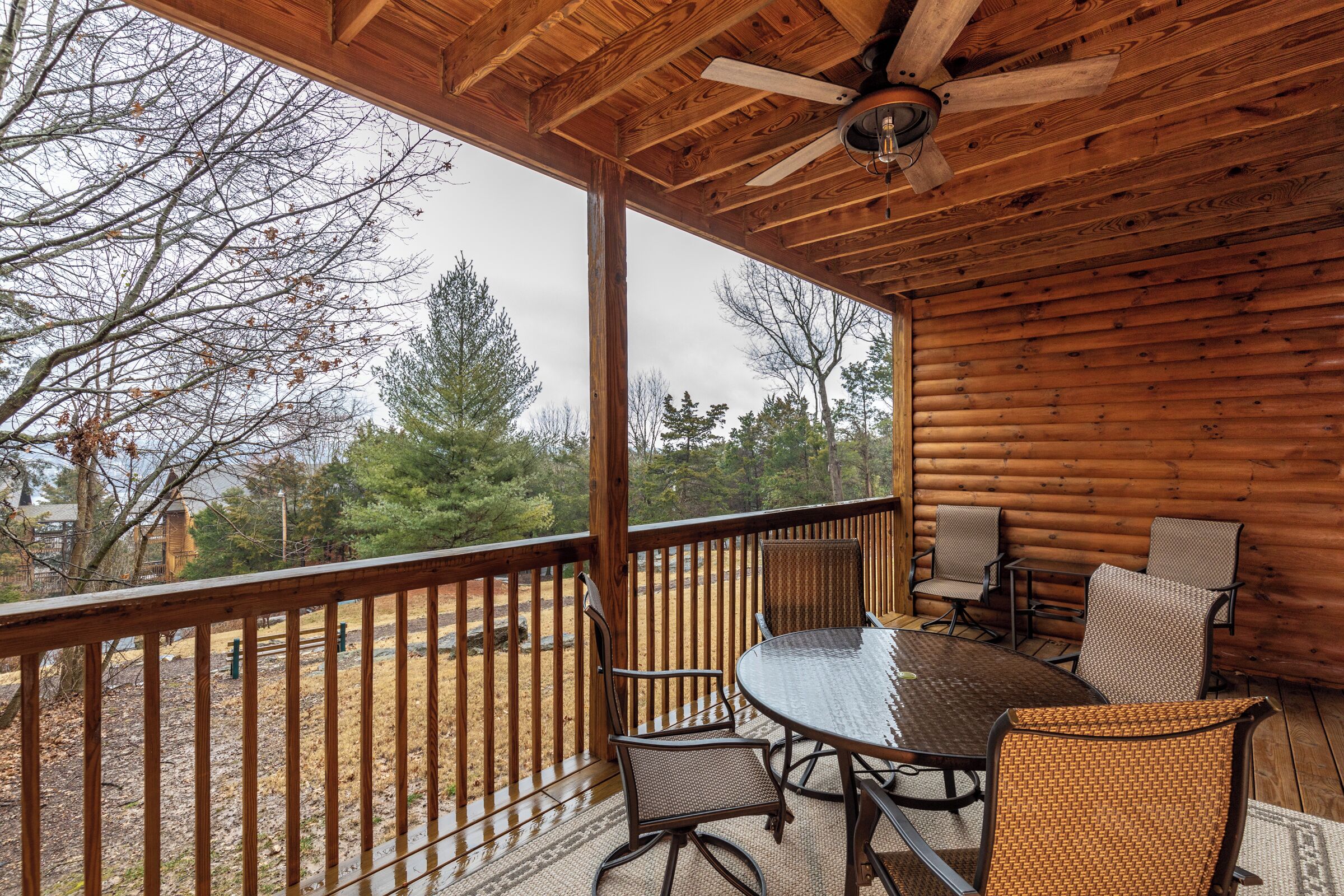 A wooden deck with a table and chairs, overlooking a natural landscape.