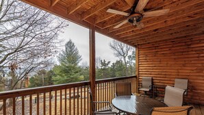 A wooden deck with a table and chairs, overlooking a natural landscape.