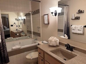 A bathroom with a bathtub, a sink, a toilet, and a large mirror. - 2BR Village At Indian Point 705 near SDC-Free Tickets Daily up to $500 Value (Branson)