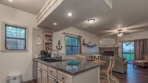 A spacious kitchen with a large island, a dining area with a round table, and a cozy seating area with a fireplace. - 2BR Village At Indian Point 705 near SDC-Free Tickets Daily up to $500 Value (Branson)