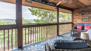 A wooden deck with a ceiling fan, a sofa with cushions, and a view of greenery and hills. - 2BR Village At Indian Point 711 near SDC-Free Tickets Daily up to $500 Value (Branson)