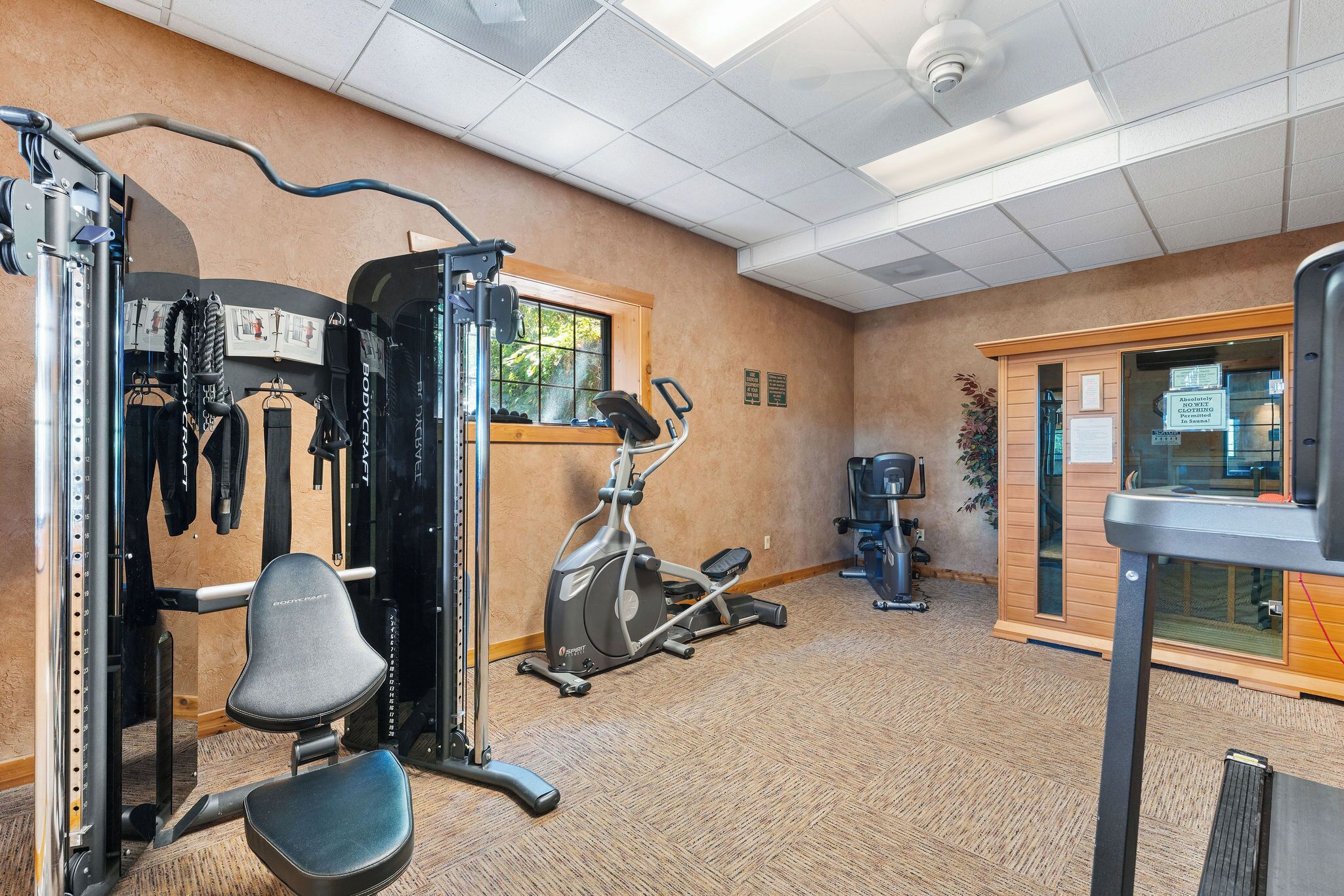 A gym with exercise equipment, a window, and a door.