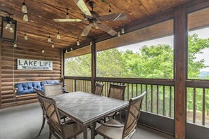 Eine Holzterrasse mit Tisch und StĂŒhlen, einem Deckenventilator und einem Schild, auf dem steht 'LAKE LIFE BEGINS THIS WAY'.