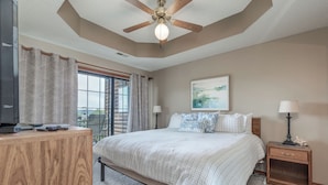 A bedroom with a bed, a desk, a nightstand, a ceiling fan, and a window with curtains. - 2BR Village At Indian Point 905 near SDC-Free Tickets Daily up to $500 (Branson)