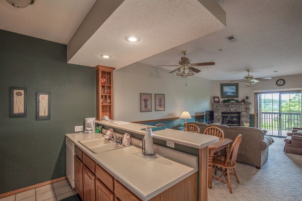 A kitchen with a central island, wooden cabinets, and a dining area with chairs. - 2BR Village At Indian Point 1007 near SDC-Free Tickets Daily  up to $500 (Branson)