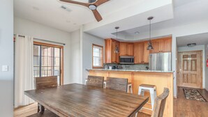 A spacious kitchen with wooden cabinets, a stainless steel refrigerator, and a dining area with a wooden table and chairs.