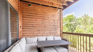 A wooden deck with wicker furniture and a glass door.