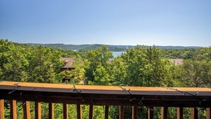 Eine Holzterrasse mit Blick auf einen See und umliegende Grünflächen.