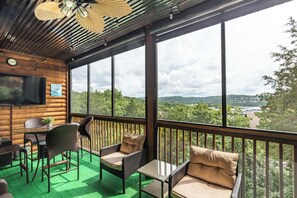 Una cabaña de madera con balcón, amueblada con sillas de mimbre y una mesa, con vistas a un paisaje pintoresco.