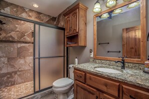 Une salle de bain équipée d’une douche, de toilettes, d’un lavabo et d’un grand miroir.