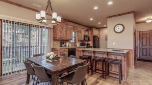 A spacious kitchen with wooden cabinets, a large island, and a dining area with a wooden table and chairs. - 2BR Village At Indian Point 1504  near SDC - Free Tickets Daily up to $500 (Branson)