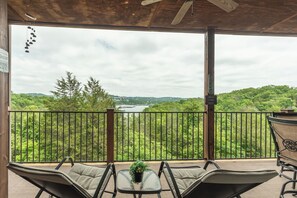 A covered balcony with a view of a lake, a table with chairs, and a sign indicating a smoke-free area.