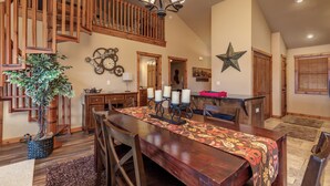 A spacious dining area with a wooden staircase, a chandelier, and a large star decoration on the wall. - 2BR+Loft Village At Indian Point 1509 near SDC- Free Tickets Daily up to $500 (Branson)