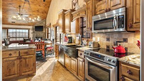 A spacious kitchen with wooden cabinets, a stone fireplace, and a large island. - 2BR Village At Indian Point 1512 near SDC - Free Tickets Daily up to $500 (Branson)