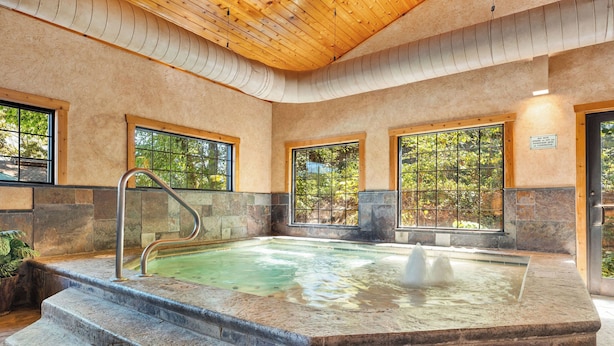 A hot tub with stone steps leading up to it, surrounded by stone walls and large windows. - 2BR Village At Indian Point 2102 near SDC - Free Tickets Daily up to $500 (Branson)