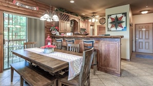 A wooden dining area with a table, chairs, and a kitchen with wooden cabinets and a star-shaped wall decoration. - 2BR Village At Indian Point 2102 near SDC - Free Tickets Daily up to $500 (Branson)