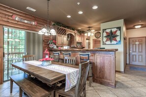 A wooden dining area with a table, chairs, and a kitchen with wooden cabinets and a star-shaped wall decoration.