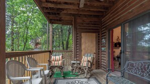 A wooden deck with rocking chairs and a bench, a glass door leading inside, and a view of trees. - 2BR Village At Indian Point 2004 near SDC - Free Tickets Daily up to $500 (Branson)