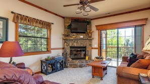 A cozy living room with a stone fireplace, leather sofas, a wooden coffee table, and a ceiling fan. - 2BR Village At Indian Point 2005 near SDC - Free Tickets Daily up to $500 (Branson)
