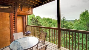 Une terrasse en bois avec une table et des chaises en verre, offrant une vue sur un paysage verdoyant et luxuriant.