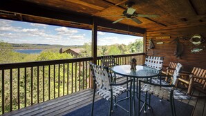 A wooden deck with a table and chairs, a ceiling fan, and a view of a lake and trees. - 2BR Village At Indian Point 2009 near SDC - Free Tickets Daily up to $500 (Branson)