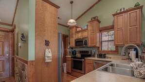 A kitchen with wooden cabinets, a stainless steel refrigerator, a microwave, and a sink. - 2BR Village At Indian Point 2009 near SDC - Free Tickets Daily up to $500 (Branson)