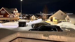 Ein Wohngebiet bei Nacht mit Häusern, einer Straßenlaterne und verschneitem Grund.