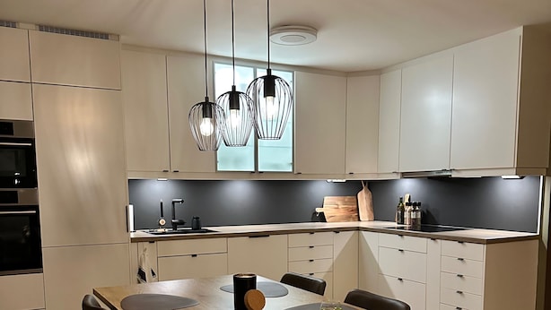 Eine moderne Küche mit einem Holzespeisetisch, schwarzen Stühlen und Pendelleuchten.