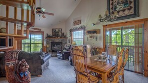 A spacious living room with a fireplace, wooden dining table, and comfortable seating.