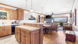 A spacious kitchen with wooden cabinets, a large island, and a dining area with a view. - 2BR Village At Indian Point 1607 near SDC - Free Tickets Daily up to $500 (Branson)