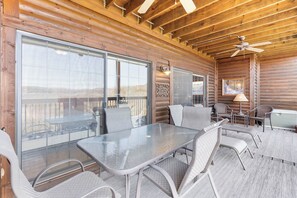 Una cabaña de madera con un comedor acristalado, sillas de metal y un ventilador de techo.