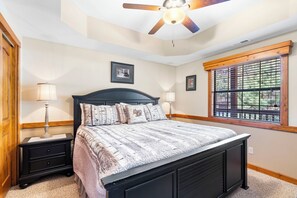 A bedroom with a bed, two bedside tables, a ceiling fan, a window with blinds, and a framed picture on the wall. - 2BR Village At Indian Point 1607 near SDC - Free Tickets Daily up to $500 (Branson)