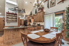 Une cuisine spacieuse avec des meubles en bois, un grand îlot central et un coin repas doté d’une table ronde.