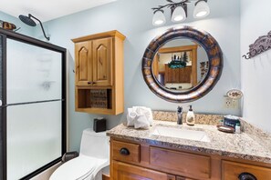 Bathroom features a large mirror, sink, toilet, and wooden vanity with a matching cabinet.