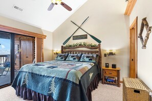 Cozy retreat with a large bed, wooden bench, and nightstand, offering a peaceful view of the outdoors.