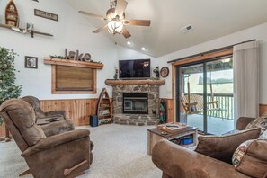 A cozy living room with a fireplace, comfortable seating, and a large TV.