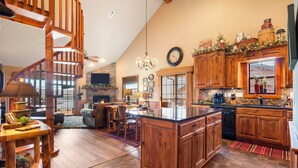 A spacious living area with a wooden staircase, a fireplace, and a kitchen with wooden cabinets and a large island. - 2BR+Loft Village At Indian Point 1712 near SDC -Free Tickets Daily up to $500 (Branson)