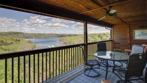 A wooden deck with a glass table and chairs, overlooking a lake and greenery. - 2BR+Loft Village At Indian 1710 Point near SDC-Free Tickets Daily up to $500 (Branson)