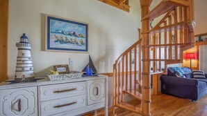 A staircase with wooden railings, a white dresser with drawers, a painting of a beach scene, and a blue sofa in a living room. - 2BR+Loft Village At Indian 1710 Point near SDC-Free Tickets Daily up to $500 (Branson)