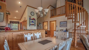 A spacious kitchen with wooden cabinets, a dining table, and a staircase leading to an upper level. - 2BR+Loft Village At Indian 1710 Point near SDC-Free Tickets Daily up to $500 (Branson)