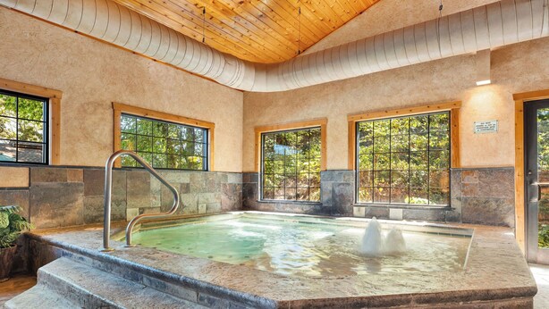 A hot tub with stone steps leading up to it, surrounded by stone walls and large windows. - 2BR Village At Indian Point 1702 next to SDC- Free Tickets Daily up to $500 (Branson)