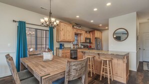 A modern kitchen with wooden cabinets, a central island with stools, and a chandelier. - 2BR Village At Indian Point 1704 near SDC - Free Tickets Daily up to $500 (Branson)